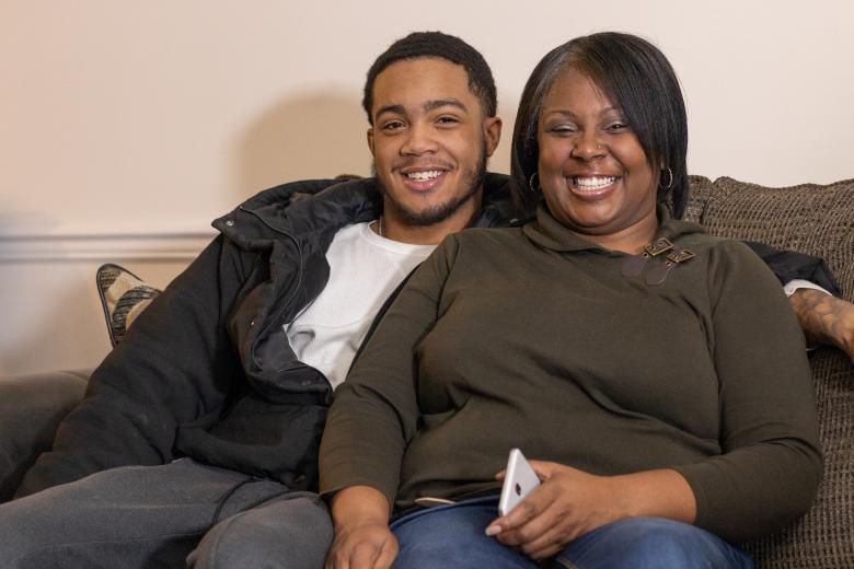 Tami and her son sit on their couch together.