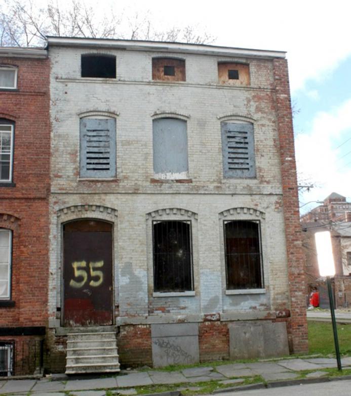 A brick three-story building with signs of wear and disrepair. 