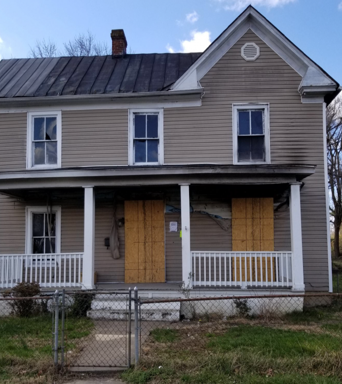 Grey house with dilapidated siding and roof.