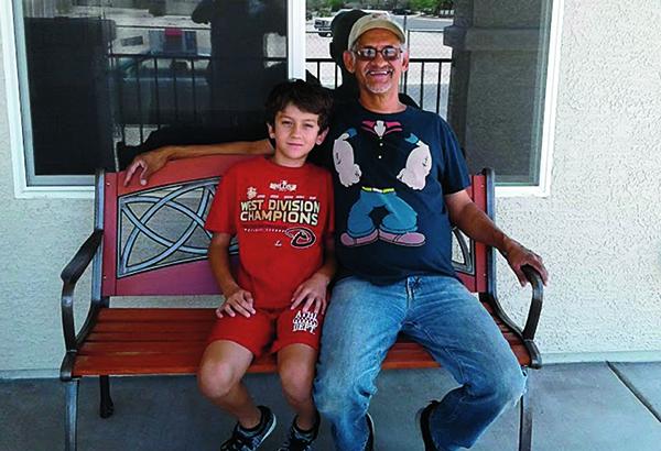 Christopher and son on bench in front of their home.