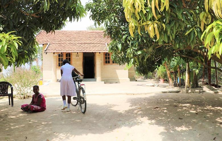 Ushathevi sitting under the shade as her daughter comes home from school.