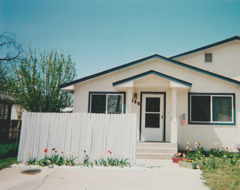 A white Habitat home with a white fence.
