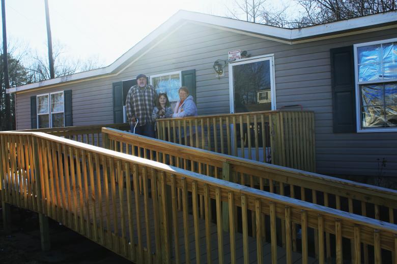 A wooden ramp leading up to a home where Robert, Theresa and Abigail stand.