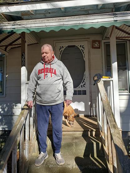 Terry stands outside his home on his entryway.