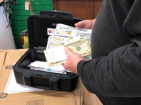 A pair of hands holding a large amount of money in bills being pulled from a pack.
