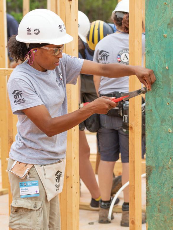 Woman in a hard hat working on a build site.