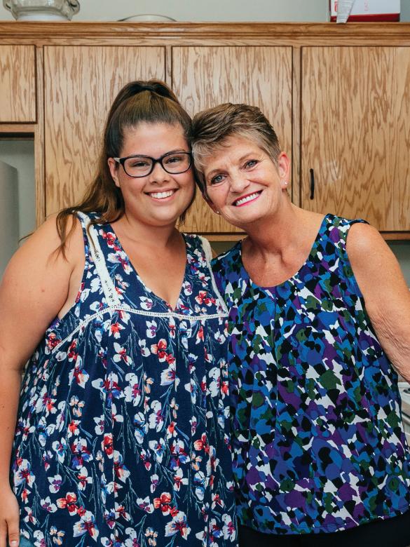 Younger woman and older woman smiling together in their kitchen.