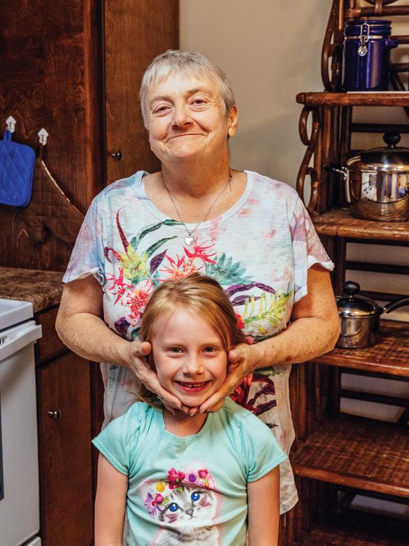 Grandmother embracing her smiling young grandchild in their home.