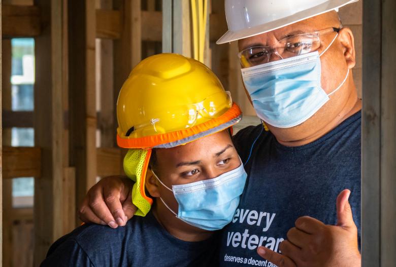 Moses on the build site hugging one of his daughters.