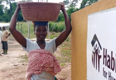 Woman in Côte d’Ivoire carrying a basin of water on her head.