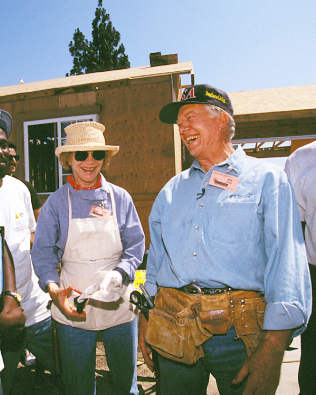 The Carters on a build site laughing together with volunteers and homeowners.
