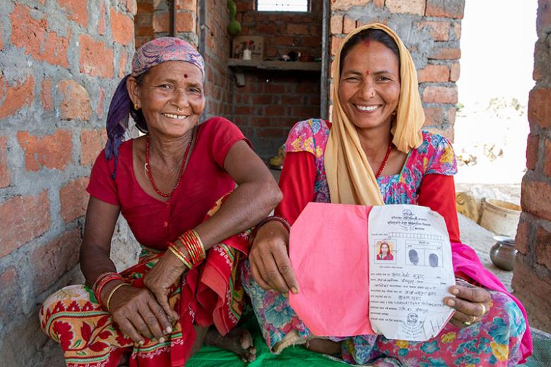 Rupa (right), with her mother Bishna, showing a land title certificate with her name