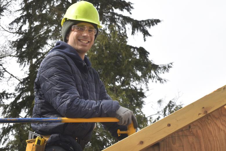 Ryan in a hardhat working on a roof.