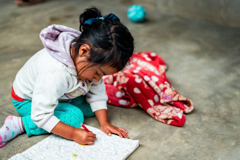 Child sitting on concrete floor while drawing