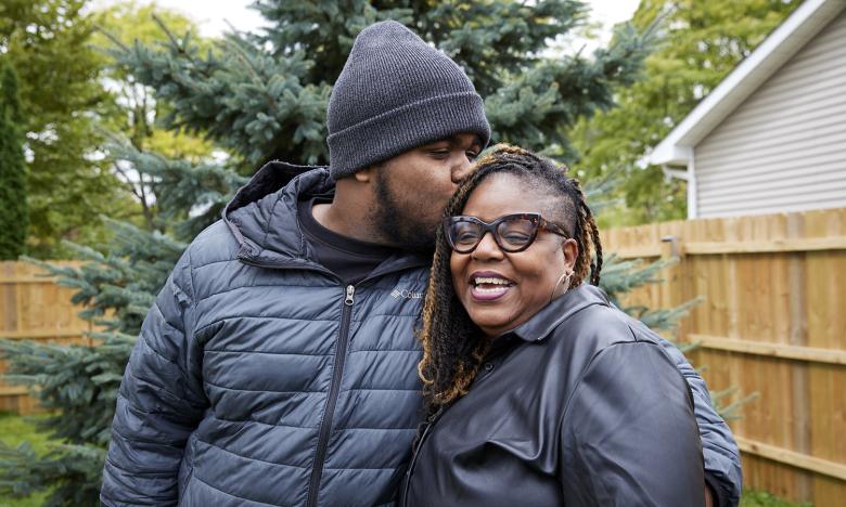 Donyelle's son kisses her head as they embrace in her yard.