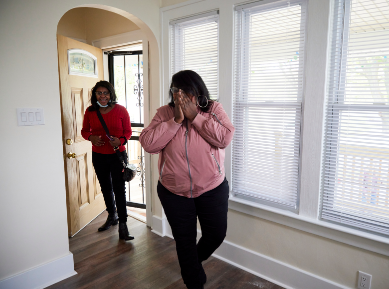 Jessica with her hands over her mouth as she and her daughter walk into their new home for the first time.