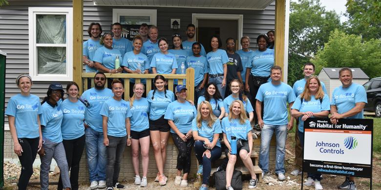 Group photo of Johnson Controls employees in matching light blue shirts volunteering on a Habitat build.
