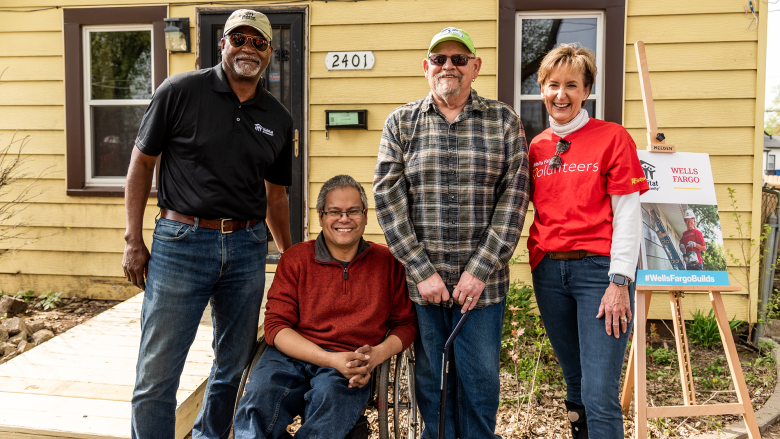 Robert and his son in front of his yellow house with volunteers.