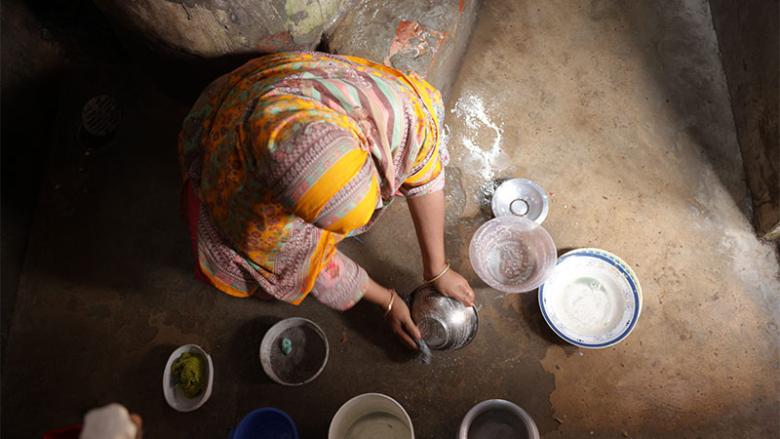 Woman washing dishes in Duaripara informal settlement, Dhaka