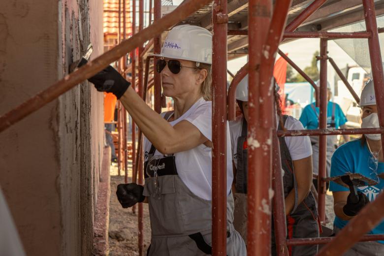 Woman working on the siding of a house during a Hope Build