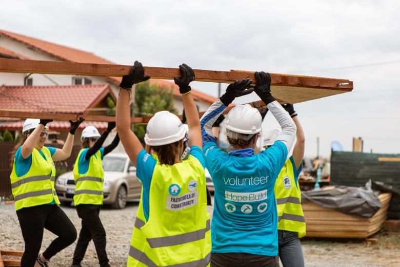 Volunteers lifting a house wall frame on the construction site