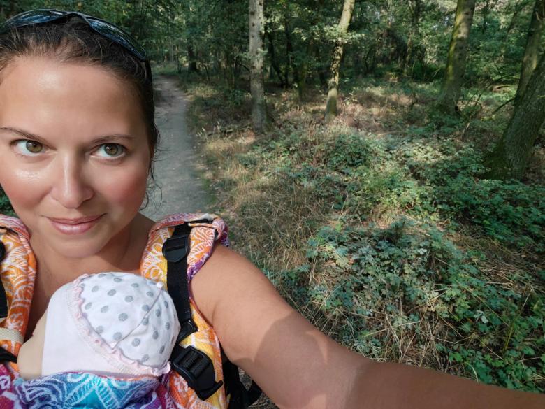 Mother walking with her child in a baby carrier in nature