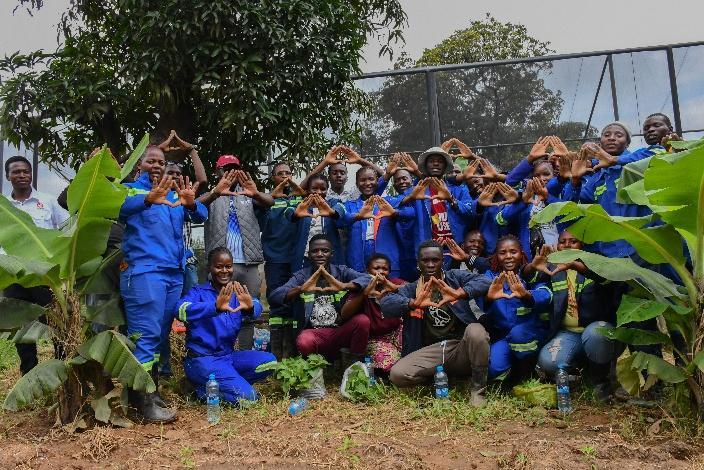Group of youth in overalls pose for a photo at a garden